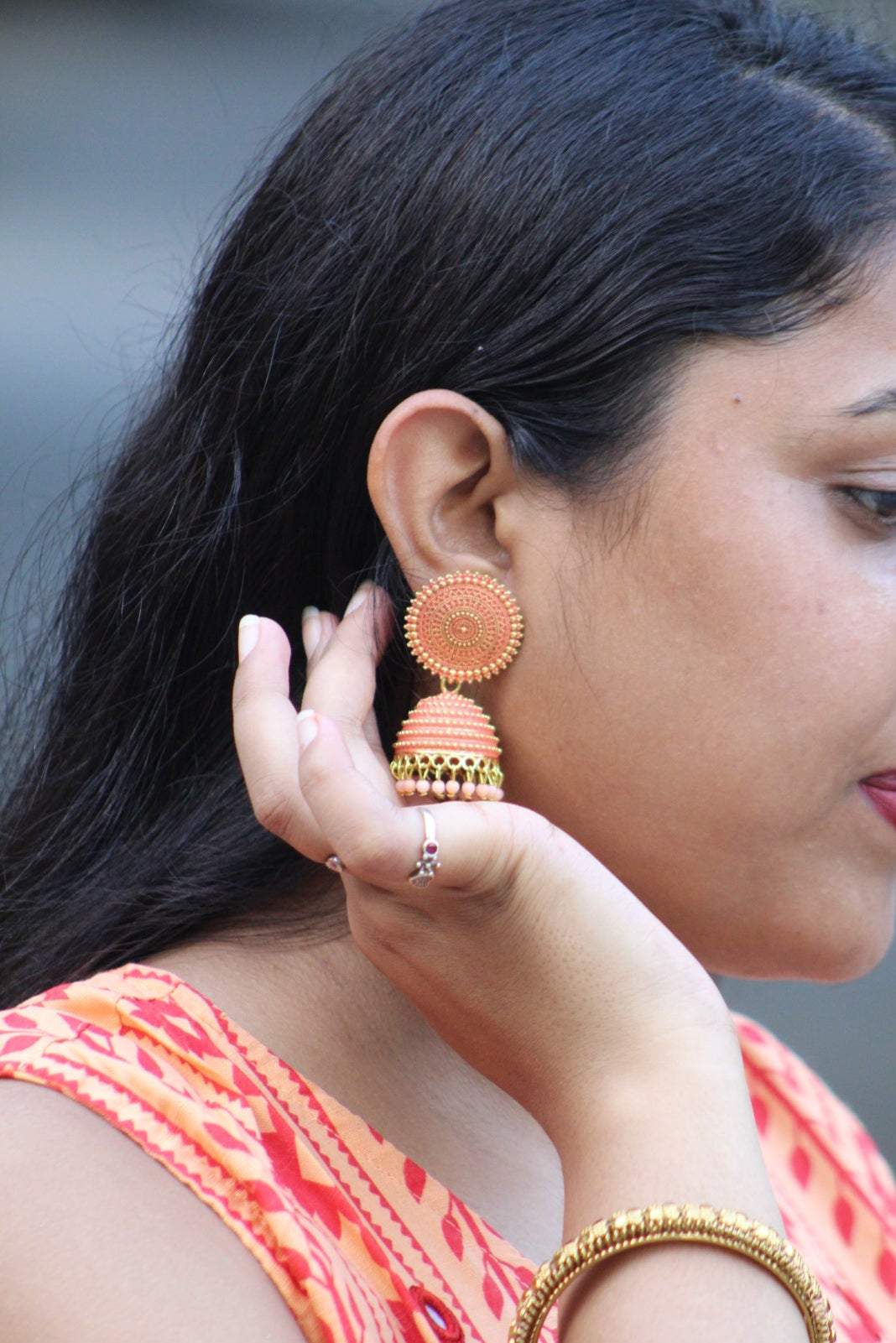 Woman adjusting an earring with a blurred background