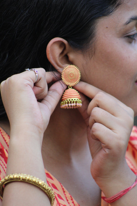 Person wearing gold earrings with a close-up of hands adjusting them.